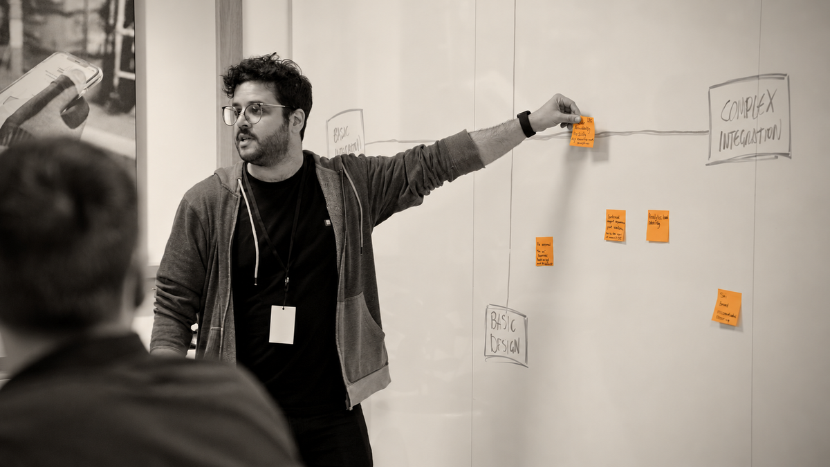Rod facilitating a workshop, placing a sticky note on a whiteboard while talking with participants.